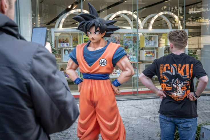 A tourist wearing a T-shirt of Dragon Ball has his photographs taken with a statue of Dragon Ball character "Son Goku" in Tokyo