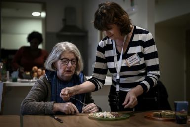 A health care worker (R) tends helps a patient with Alzheimer's eat lunch