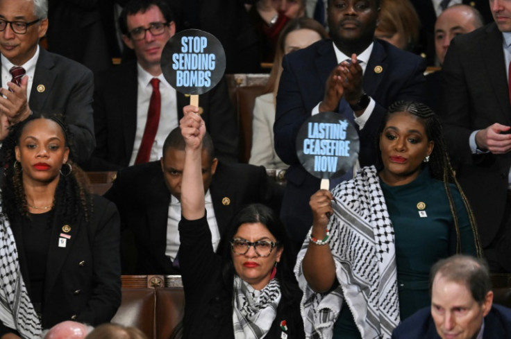 Representative Rashida Tlaib, Democrat of Michigan, and Representative Cori Bush, Democrat of Missouri, hold signs reading "Stop Sending Bombs" and "Lasting Ceasfire Now" as President Joe Biden delivers the State of the Union address