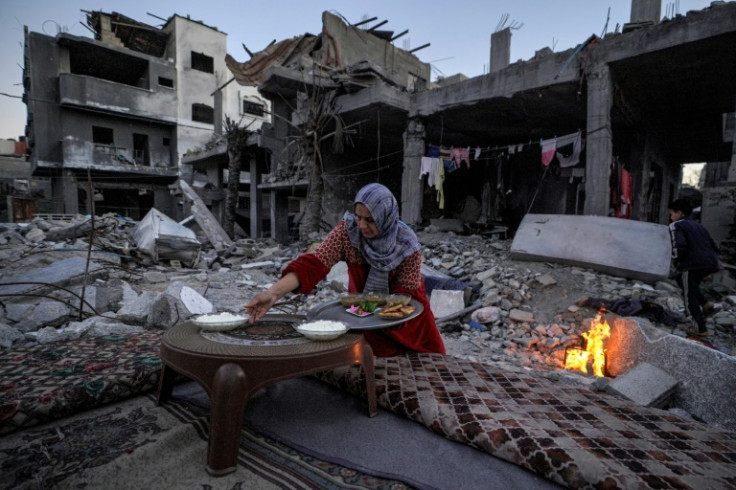 A Palestinian woman prepares a traditional Ramadan iftar meal amid the ruins of her family's house
