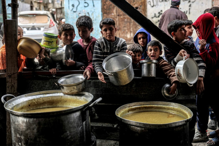 Children queue for food ahead of iftar meal to break the daily fast on Ramadan, in southern Gaza's Rafah