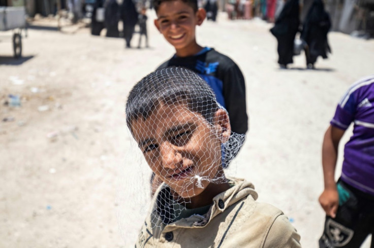 Behind the wire: A boy plays with a mesh bag over his head in the al-Hol camp holding the families of IS fighters in Syria