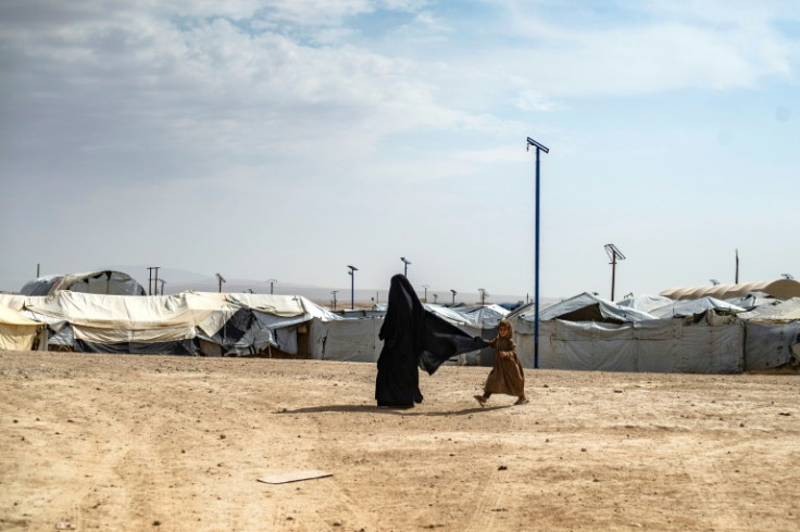 A girl walks behind her mother through the vast al-Hol camp in northeastern Syria
