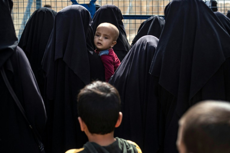 Women stand next to a fence at the al-Hol camp in Syria where Islamic State fighters' families are held