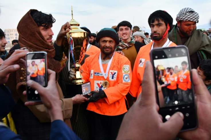 Horseman Sarwar Pahlawan (C) of the Yama Petroleum Team holds up the Buzkashi League trophy after their victory in the tournament final