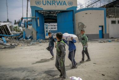 Children carry bags of flour outside an UNRWA compound after humanitarian aid was distributed in Gaza City