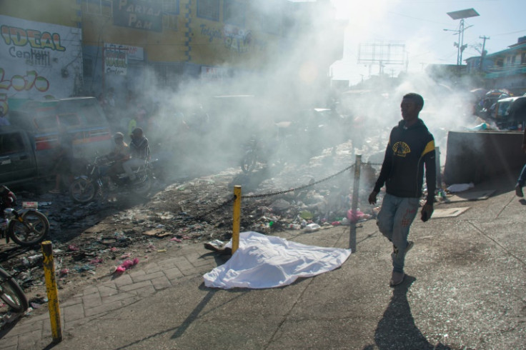 A man walks past the body of a person who was among a dozen killed in the street by gang members, in Pétionville, Port-au-Prince, Haiti