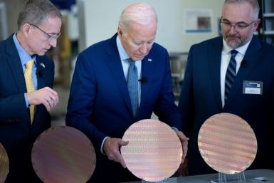 Intel CEO Pat Gelsinger (L) and Intel Factory Manager Hugh Green (R) watch as US President Joe Biden (C) looks at a semiconductor wafer during a tour at Intel Ocotillo Campus in Chandler, Arizona