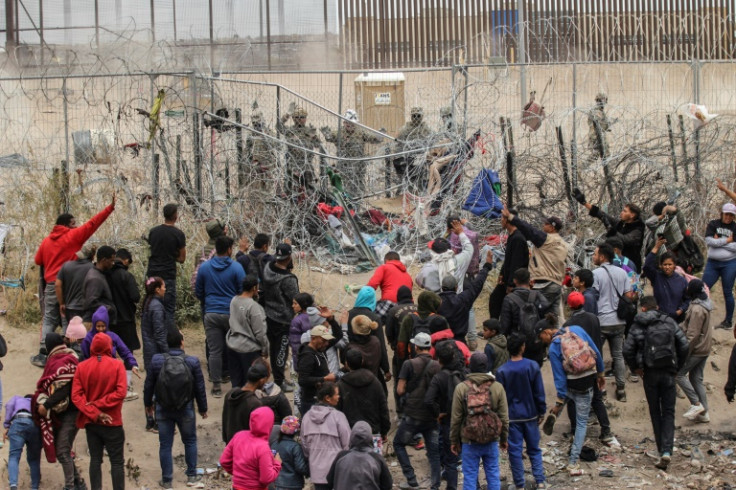 A group of migrants try to cross a barbed wire fence to reach the US from Ciudad Juarez, Mexico on March 20, 2024