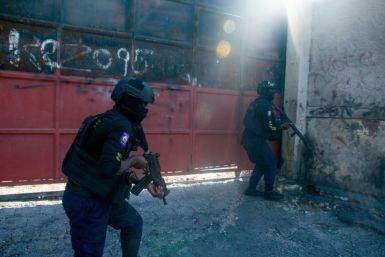 Armed police officers monitor a street after gang violence in the neighborhood on the evening of March 21, 2024, in Port-au-Prince, Haiti