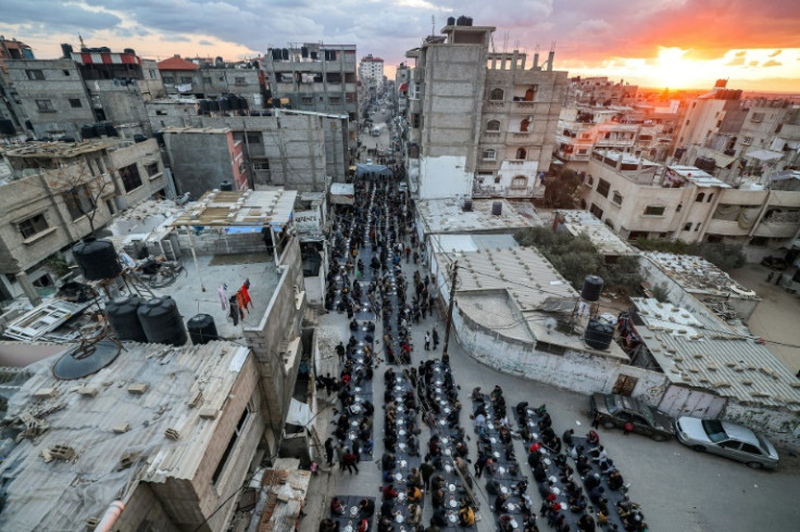People sit together for a mass 'iftar' (fast-breaking) meal organised by members of the Barbara refugee camp during the Muslim holy month of Ramadan in Rafah