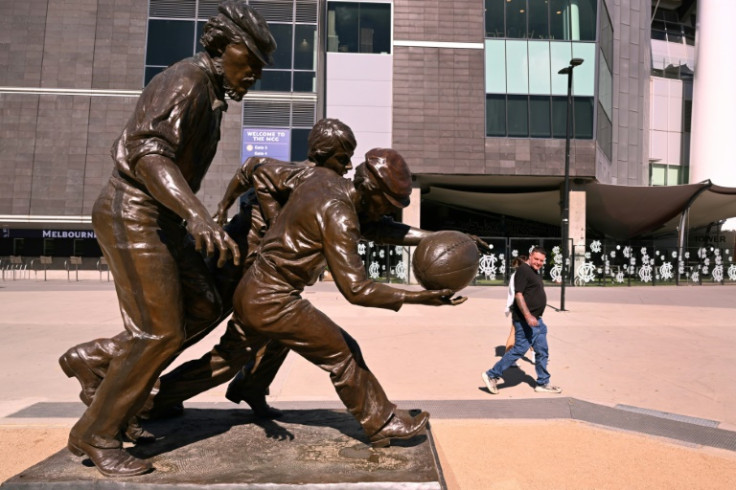 A man looks at a sculpture of Australian Rules footballers outside the Melbourne Cricket Ground