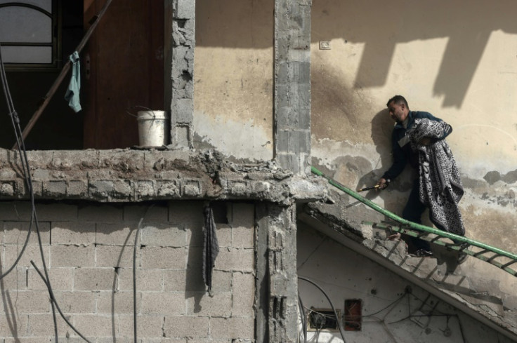 A Palestinian man carries a blanket at a building that was heavily damaged following overnight Israeli bombardment in Rafah, in the southern Gaza Strip