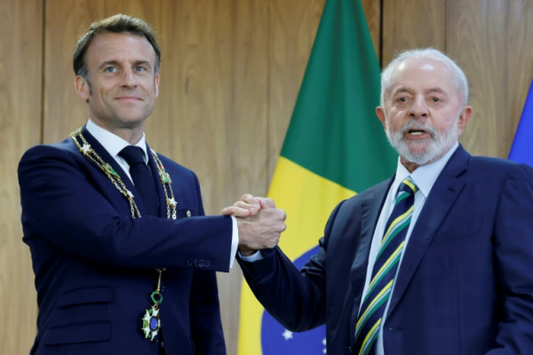 France's President Emmanuel Macron (L) wears the Order of the Southern Cross decoration while posing for a picture with Brazil's President Luiz Inacio Lula da Silva (R) at the Planalto Palace in Brasilia