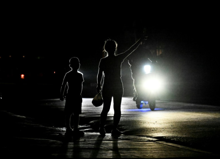 A woman signals a motorist for a ride during a blackout in Bauta in Cuba's Artemisa province