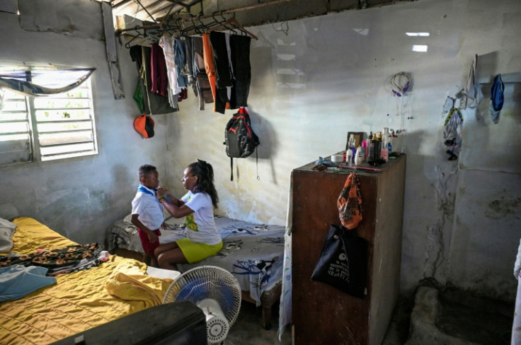 Diana Ruiz helps her son slip off his school uniform in their Havana home