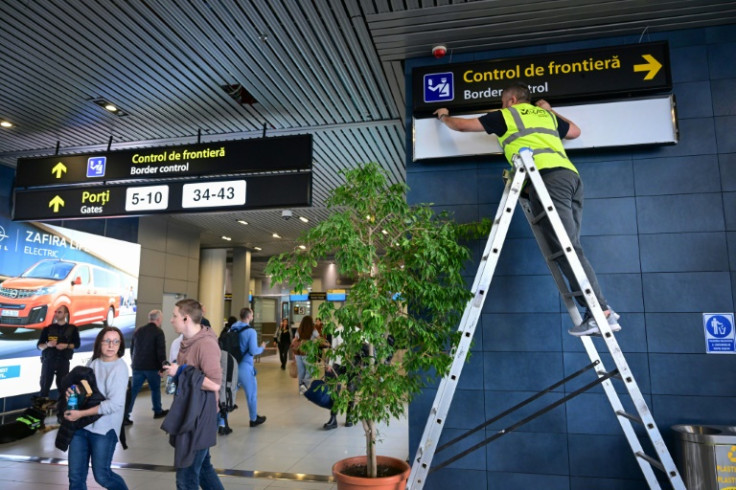 A Romanian worker changes the signs for passengers at Henri Coanda International Airport ahead of Romania and Bulgaria taking a first step into the Schengen visa free travel area on Sunday