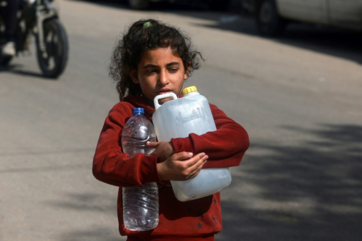 A Palestinian girl carries water at a makeshift camp for displaced people in Rafah in the southern Gaza Strip on March 30, 2024