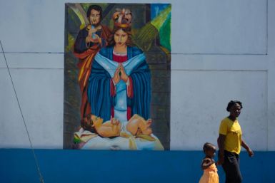 A woman passes with her child in front of a mural on a church wall in Port-au-Prince on Good Friday on March 29, 2024