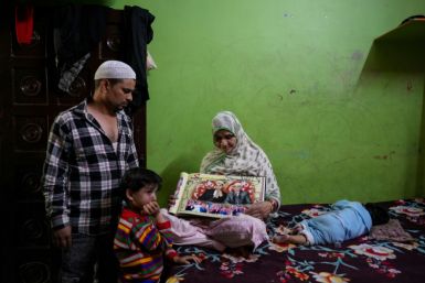 The mother of Faheem Qureshi, who was killed in anti-Muslim riots in February, sits with a picture of her son