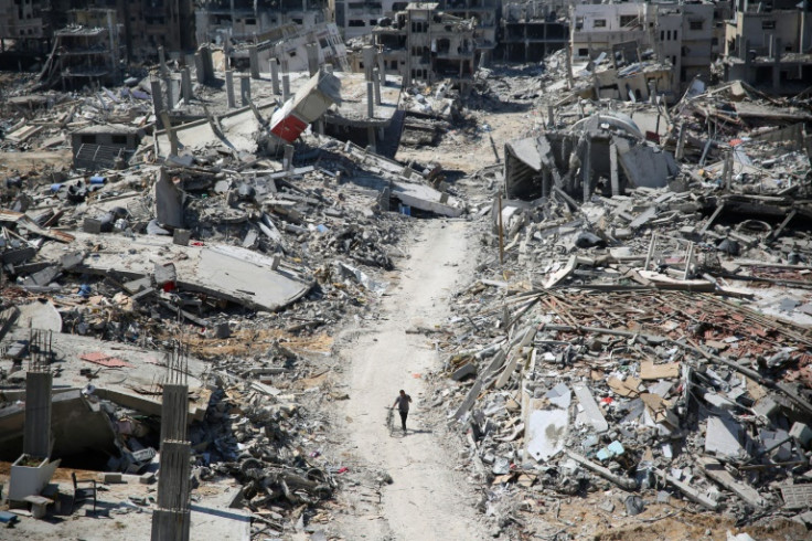 A man pushes a bicycle amid buildings devastated by bombardment around Gaza's Al-Shifa hospital, on April 3, 2024