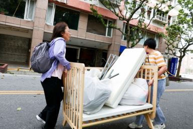 Residents salvage a cot from the damaged Tongshuai Building following the earthquake in Hualien