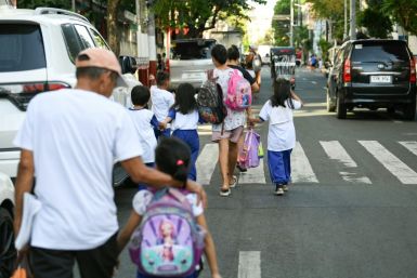 Parents accompany their children from school in Manila after dangerously high temperatures forced the Philippines to suspend in-person classes in 5,288 schools