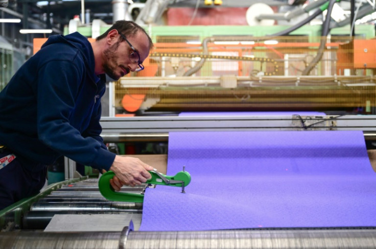 A Mondo employee works on a section of the purple athletics track for the Paris Olympics