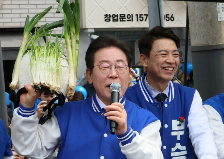 South Korea's main opposition Democratic Party leader Lee Jae-myung holds a helmet decorated with green onions during a campaign event as he makes a point about high prices