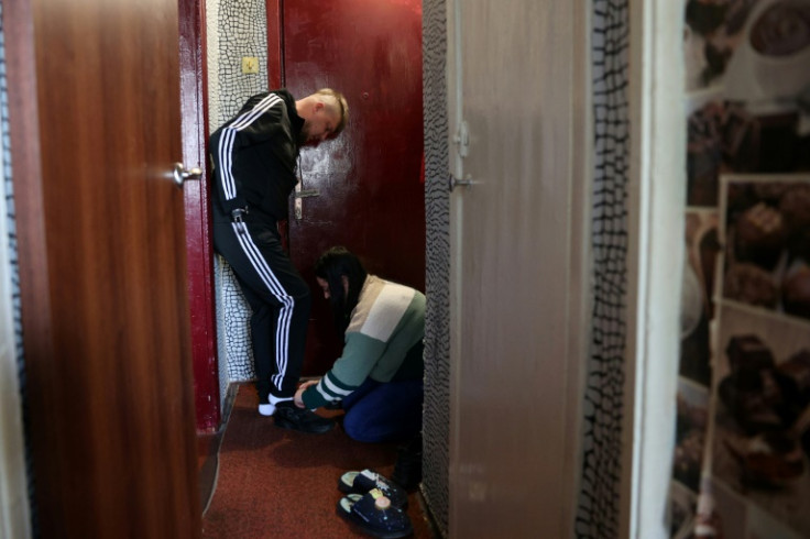 Veronika Kucherenko, 25, helps her husband put on his shoes