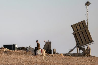 A boy rides a donkey near one of the batteries of Israel's Iron Dome missile defence system at a village not recognised by Israeli authorities in the southern Negev desert on April 14, 2024.