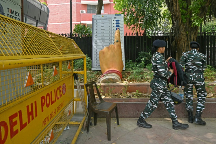 Indian security personnel walk past a model of an electronic voting machine displayed outside the office of the Election Commission of India in New Delhi