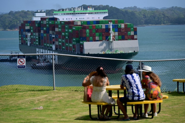 Tourists watch a cargo ship pass through the Panama Canal's Agua Clara Locks