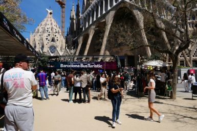 Tourists walk past the Sagrada Familia basilica in Barcelona
