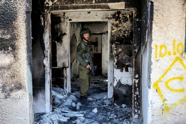 An Israeli army soldier stands in a burnt building in kibbutz Kfar Aza in the wake of Hamas's October 7 attack