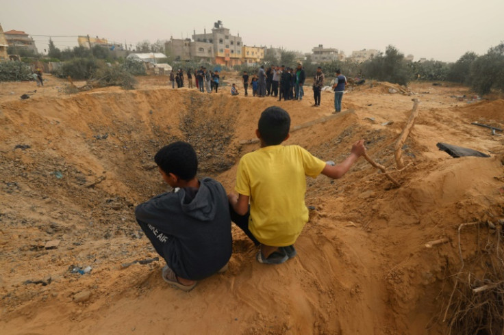 Two Palestinian boys look at a huge crater following an overnight Israeli bombardment in Rafah, southern Gaza Strip