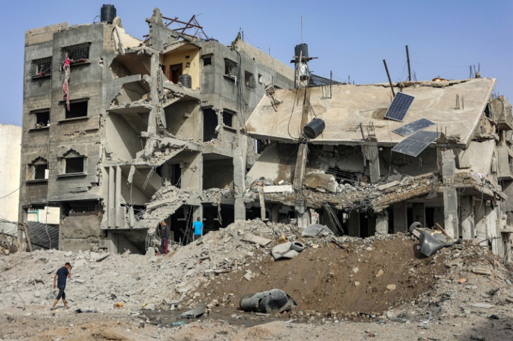 People inspect the wreckage of a partially-collapsed building in Gaza City