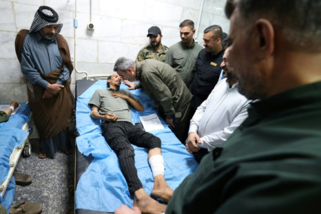 Abu Fadak Al-Mohammedawi (C-R), the chief of staff of Iraq's Popular Mobilisation Forces, visits a man at a hospital in Hilla in the central province of Babylon after he was wounded in an explosion overnight