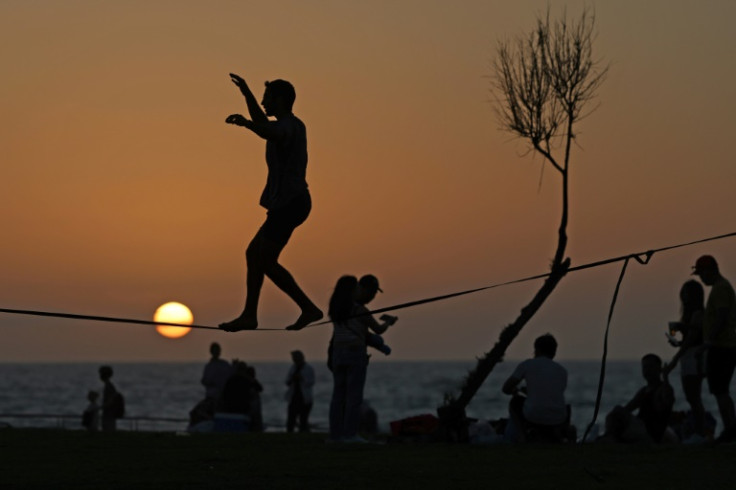 A man balances on a wire at a beach in the Israeli coastal city of Tel Aviv at sunset, as war rages in Gaza and the region walks a tightrope to avoid wider conflict