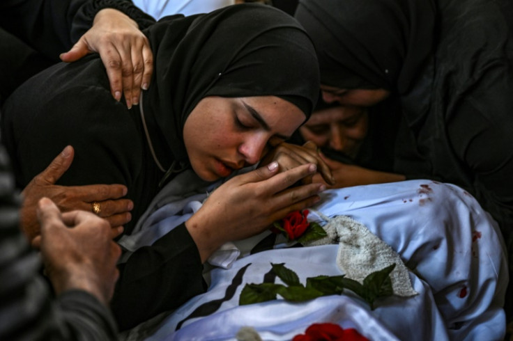 A funeral procession for 13 Palestinians killed in the Israeli army raid passed through roads piled with rubble