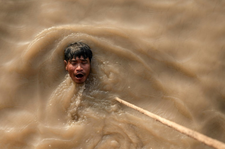 A man swims after a dive to recover a sunken ship in the Yangon River; scrap dealers buy the metal and melt it down to be used again