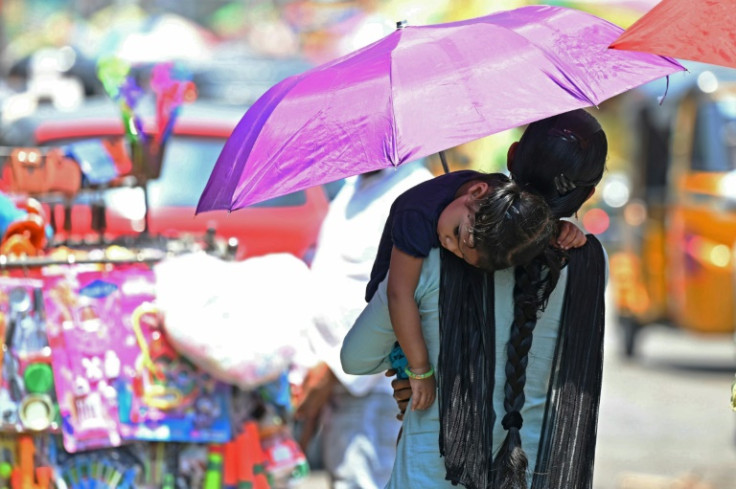 A woman carries her daughter through a market in Hyderabad as much of South and Southeast Asia endure heatwaves