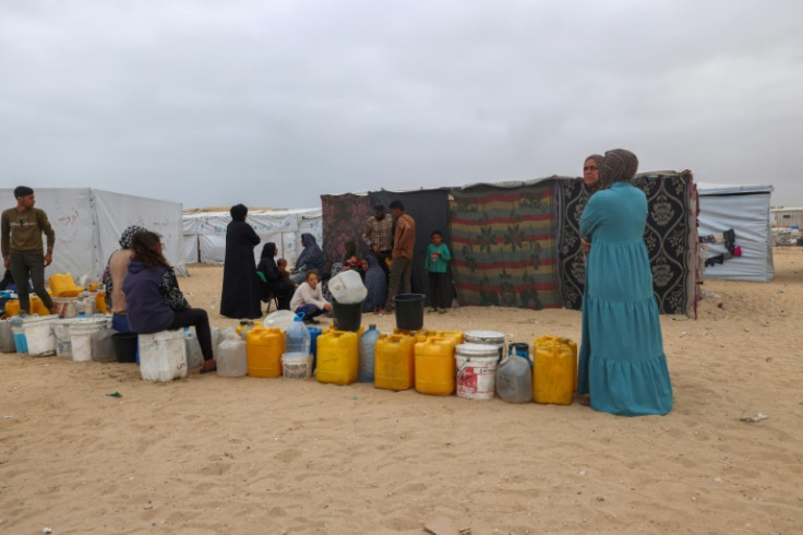 Displaced Palestinians wait by containers for water supply at their tent camp in Rafah, where Israel says it will send in ground troops against Hamas