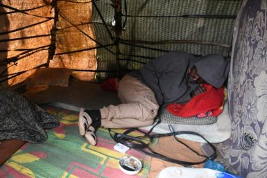 A migrant rests inside a makeshift tent at a camp in Jebeniana