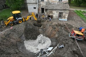 Utility workers operate next to a crater in the courtyard of a hospital in Kharkiv