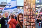 A protester with a zip over her mouth holds up photographs of the Israeli hostages at a Tel Aviv rally demanding that the government strike a deal with Hamas for their release