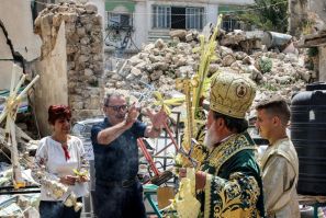 Greek Orthodox Archbishop Alexios of Tiberias throws cross-shaped palm fronds to bless worshippers from Gaza's Christian minority in a procession during the Palm Sunday service to mark the start of Holy Week for Orthodox Christians, in Gaza City
