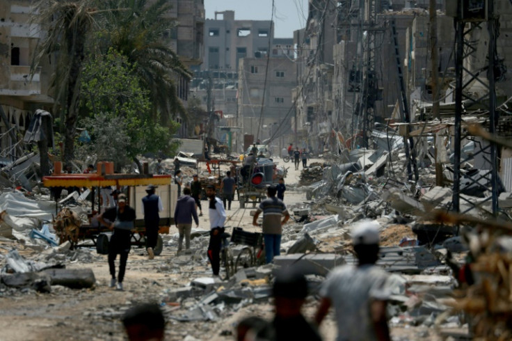 Palestinians walk amid the rubble of destroyed buildings in Nuseirat, in the central Gaza Strip on April 29, 2024