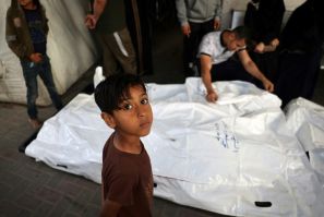 A young boy looks on as relatives of Palestinians killed in Israeli bombing mourn near their corpses in the yard of the Al-Najjar Hospital in Rafah