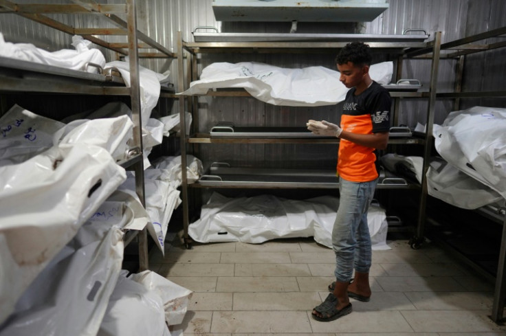 A young Palestinian who works with his father at the morgue at the Nasser Hospital in southern Gaza stands next to the bodies of people killed in the fighting who have yet to be identified